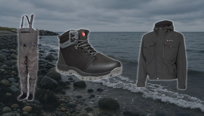 Greys Drypoint waders-s�t til skarp pris  waders, vadest�vler og jakke vist foran stenet kystlandskab.